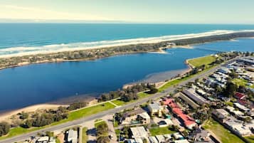 Une vue aérienne d’une zone côtière comprenant une étendue d’eau importante, un pont et une zone résidentielle avec des maisons et des routes.
