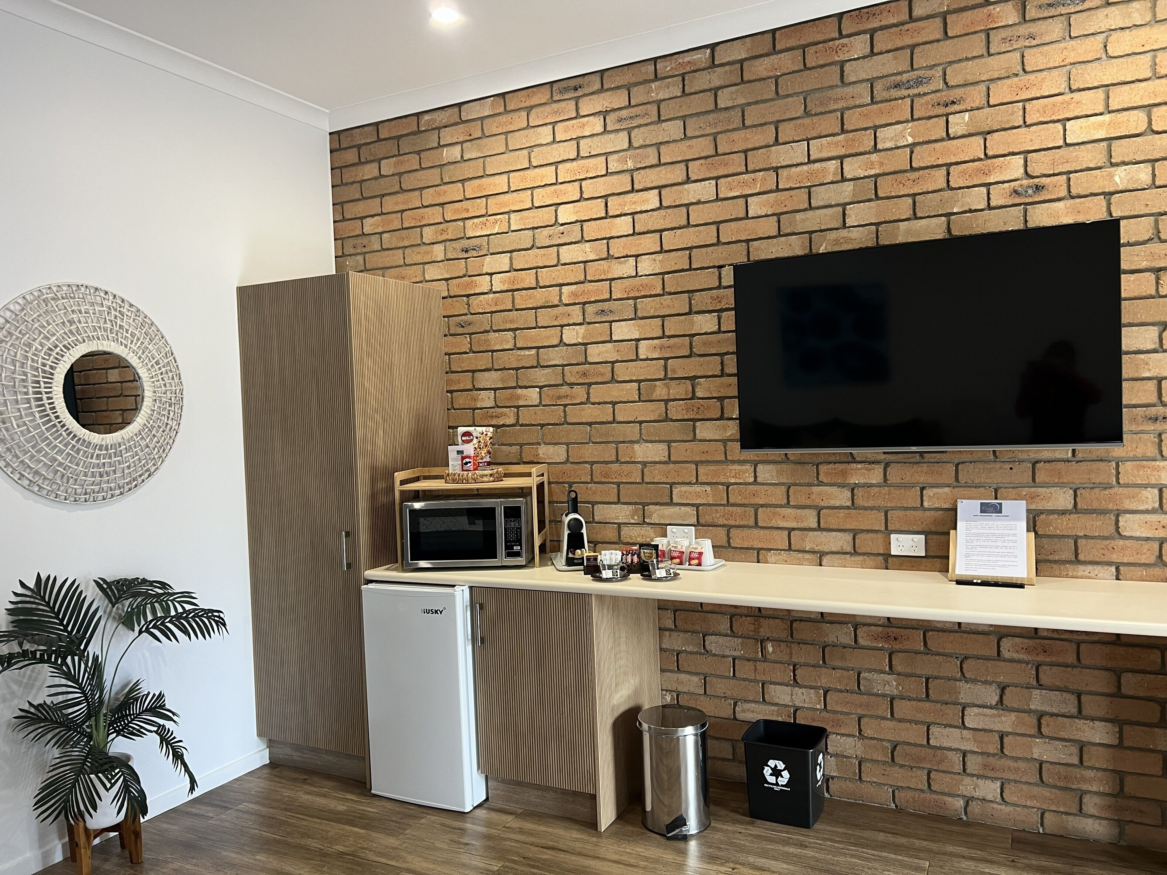 Una kitchenette con microondas, un refrigerador pequeño, un cesto de basura y un contenedor para reciclaje.