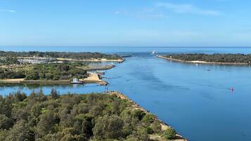 A coastal landscape with a marina, boats, and a lighthouse.