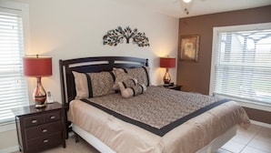 A bedroom with a bed, two nightstands, a wall decoration, and a window with blinds. - Ly53820 - Indian Ridge - 3 Bed 2 Baths Villa (Kissimmee)