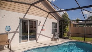 A backyard with a swimming pool, a covered patio, and a sliding glass door leading to a covered porch. - Ly53820 - Indian Ridge - 3 Bed 2 Baths Villa (Kissimmee)