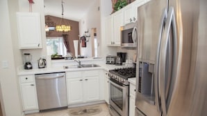 A modern kitchen with white cabinets, stainless steel appliances, and a central island. - Ly53820 - Indian Ridge - 3 Bed 2 Baths Villa (Kissimmee)