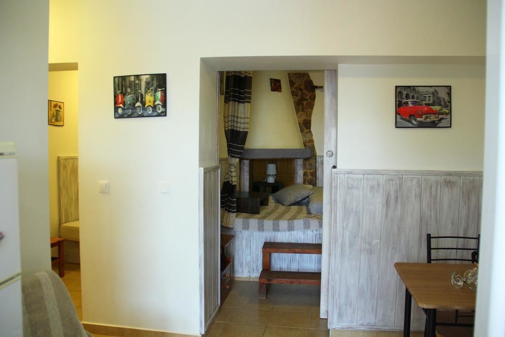 Ein gemütliches Zimmer mit einem Bett, einem kleinen Tisch und einer Bank. An den Wänden befinden sich Gemälde und auf dem Nachttisch eine Lampe.