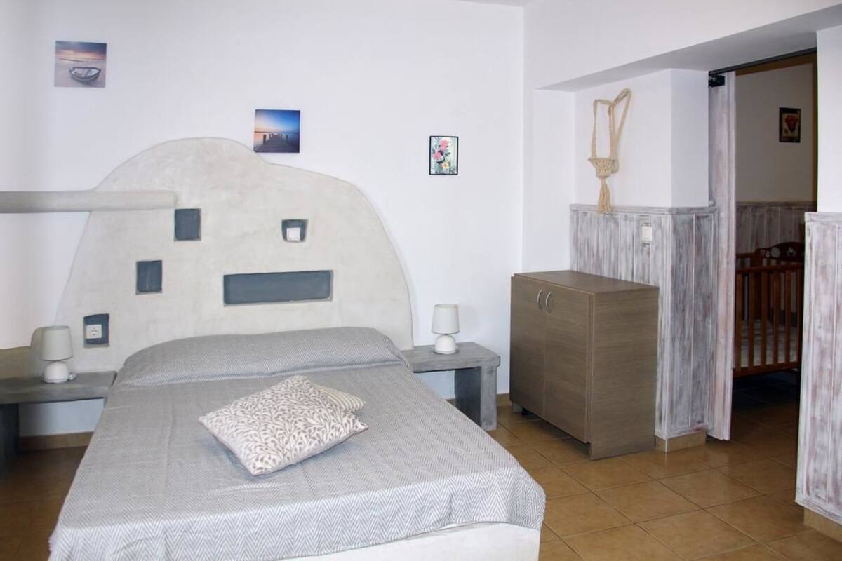 A bedroom with a bed, bedside tables, a wardrobe, and a door leading to another room.