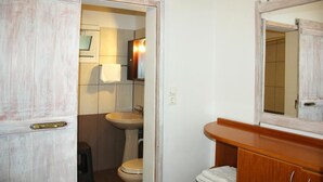 Et badeværelse med en trækommode, håndvask og toilet.