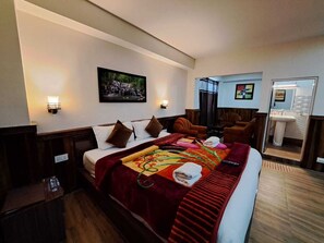 Quarto de hotel com uma cama grande, cabeceira de madeira, manta vermelha e um quadro na parede.