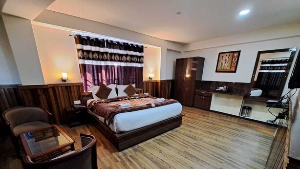 Quarto de hotel com uma cama grande, uma escrivaninha, uma cadeira, um guarda-roupa e uma televisão.