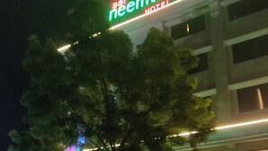 A hotel named 'Sain Neemtree' with a prominent sign, a large tree in front, and a building with multiple windows. - Sai Neem Tree Hotel (Rahata)