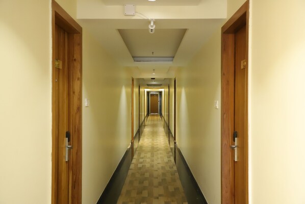Un pasillo de hotel con puertas de madera, alfombra estampada y una lámpara en el techo.