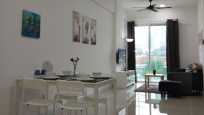 A modern living room with a dining area, a ceiling fan, and a view of the city through large windows. - Suria Next To Desa ParkCity (Kuala Lumpur)