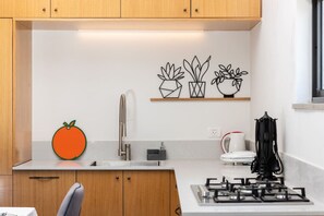 A modern kitchen with wooden cabinets, a stainless steel sink, a gas stove, and decorative wall art.