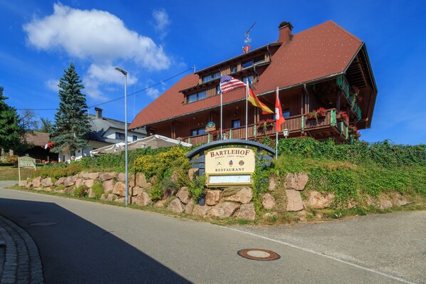 Un restaurant avec une enseigne, un toit rouge et des drapeaux.