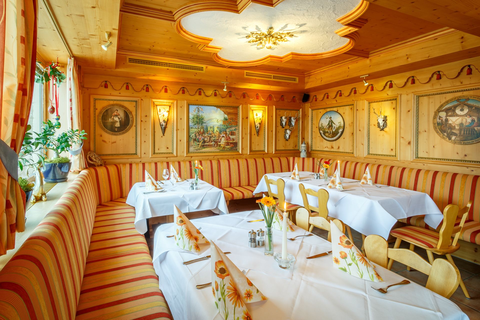 A restaurant with striped booths and tables, wooden paneling, and wall-mounted artwork.