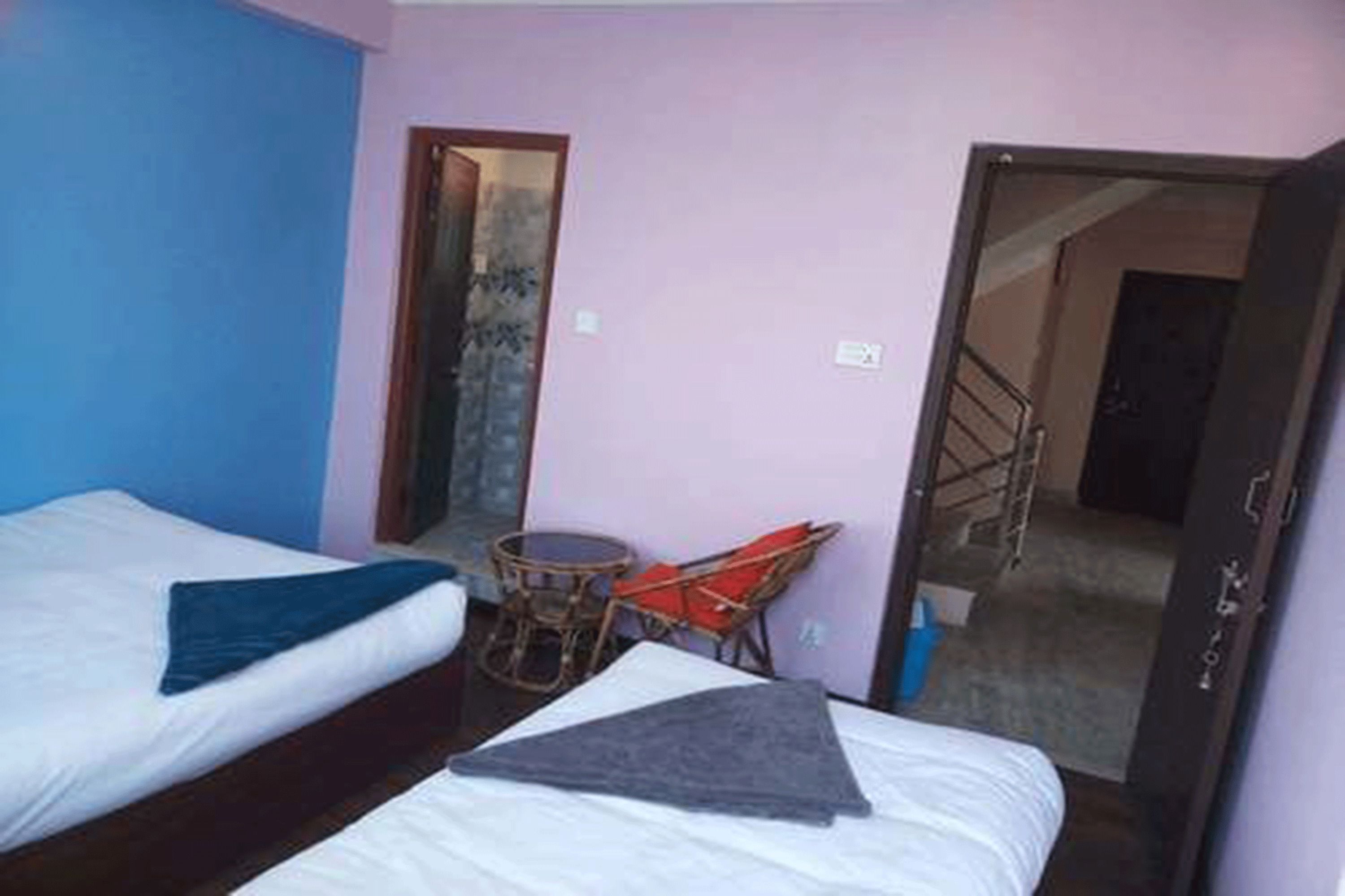 A room with two beds, a small table, and a chair.