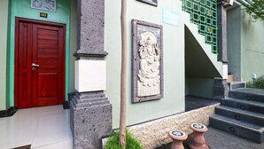 A building entrance with a red door, a stone relief sculpture, and a staircase.