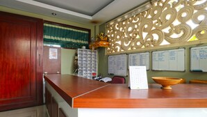 A reception area with a wooden counter, a decorative wall, and several whiteboards on the wall.