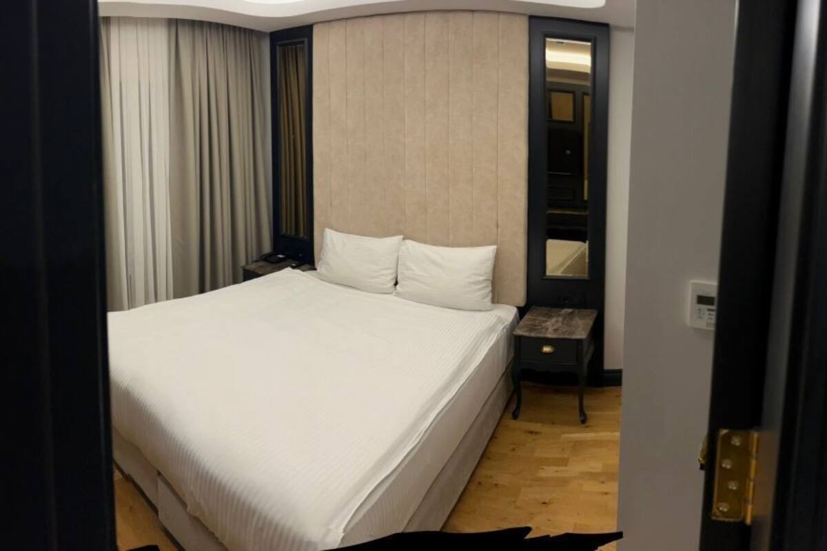 Quarto de hotel com sofá, mesa de madeira, cama e mesa de cabeceira.