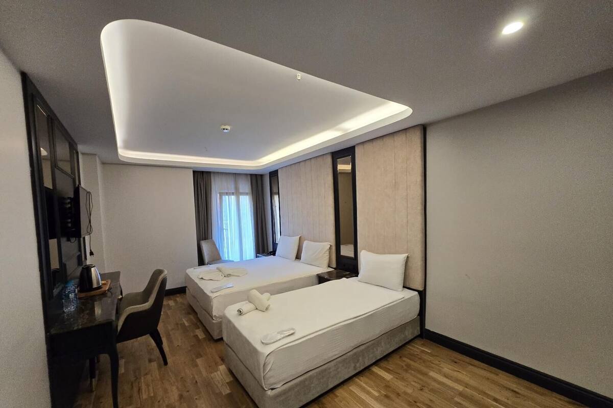 Quarto de hotel moderno com uma cama grande, uma escrivaninha com cadeira e uma televisão de tela plana.