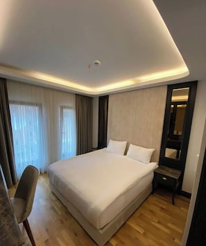 Una habitación de hotel moderna con una cama grande, un escritorio y un espejo.
