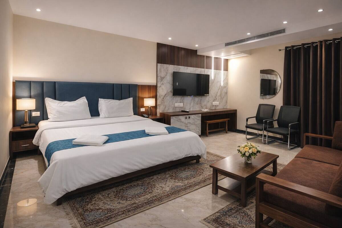 A hotel room with a large bed, a desk, a TV, two chairs, and a coffee table.