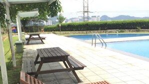A poolside area with wooden loungers and a covered seating area. - Aman Dua Apartment by SYNC (Batu Caves)