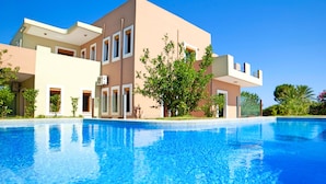 A modern two-story building with a swimming pool in front. - Island Suites (Apokoronas)