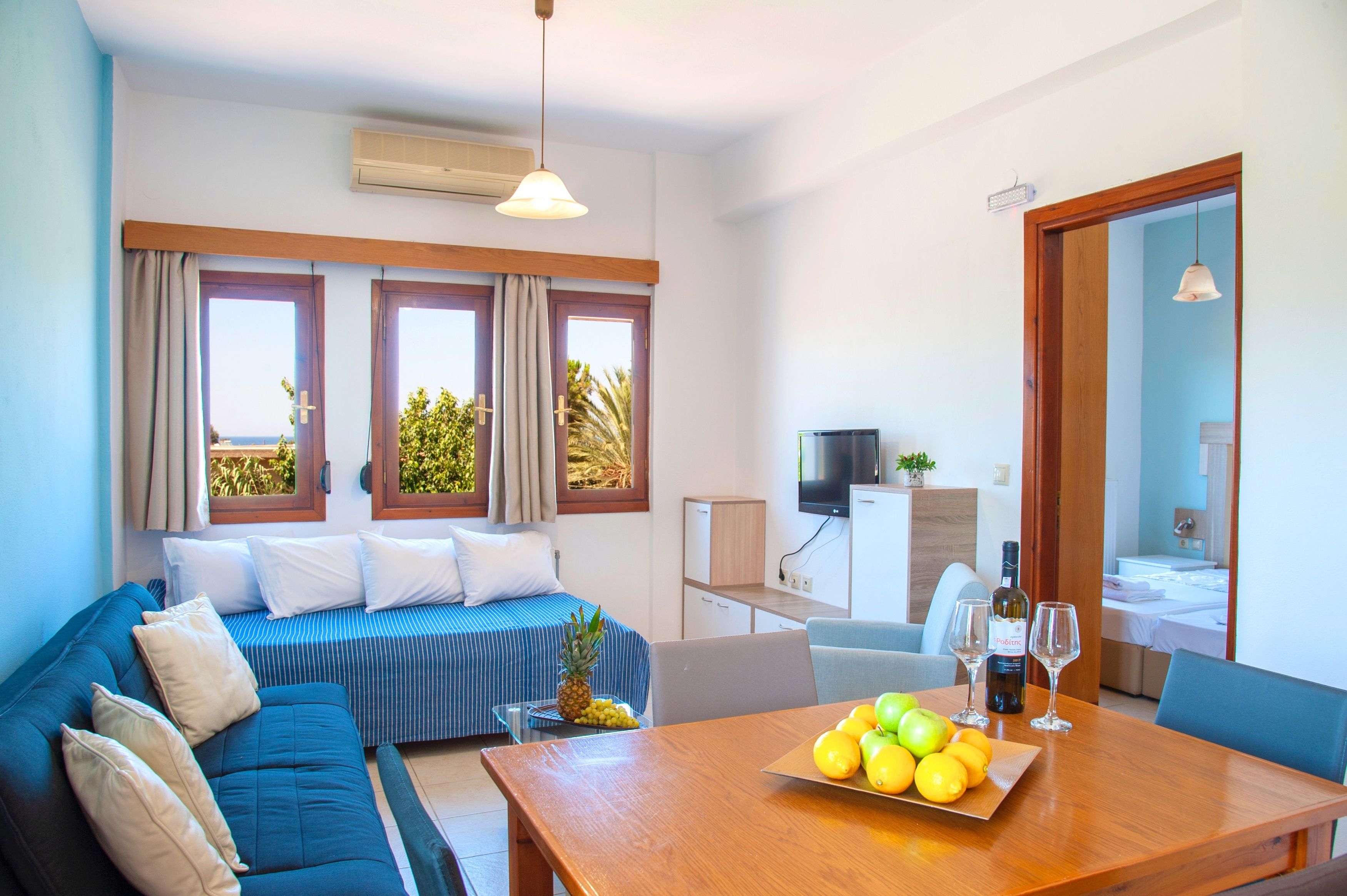 Una habitación moderna con sofá, mesa de comedor con fruta y televisor.