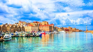 A harbor with boats, historic buildings, and a prominent tower. - Island Suites (Apokoronas)