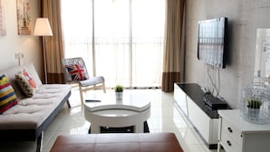 A modern living room with a sofa, a chair, a coffee table, a TV, and a cabinet. - Casa Indah by SYNC (Petaling Jaya)