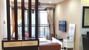 A modern hotel room with a large window, a desk, a chair, a television, and a decorative panel. - Casa Indah by SYNC (Petaling Jaya)