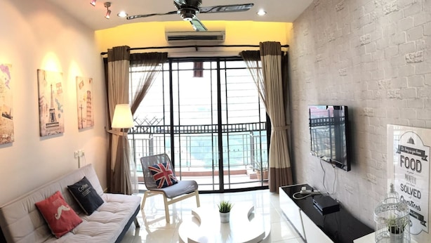 A modern living room with a sofa, coffee table, and a TV mounted on the wall. - Casa Indah by SYNC (Petaling Jaya)