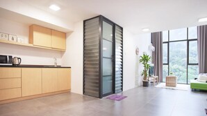 Una cocina moderna con armarios de madera, microondas integrado y un amplio ventanal con vistas a zonas verdes.