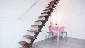 Una escalera moderna de diseño original que conduce a un pequeño comedor con una mesa y dos taburetes.