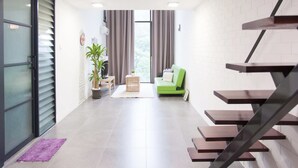 Una sala de estar moderna con una escalera, un sofá verde, una mesita y una planta en maceta.