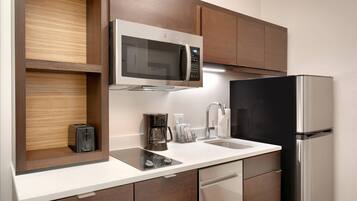 Una cocina moderna con microondas integrado, cafetera y refrigerador.