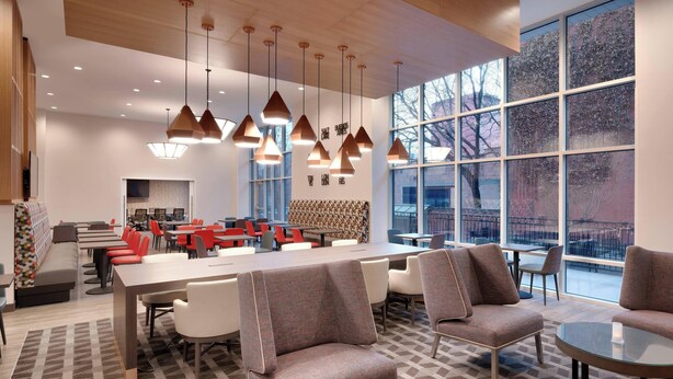 A modern dining area with high tables and chairs, pendant lighting, and large windows offering a view of the outside. - TownePlace Suites by Marriott Salt Lake City Downtown (Salt Lake City)
