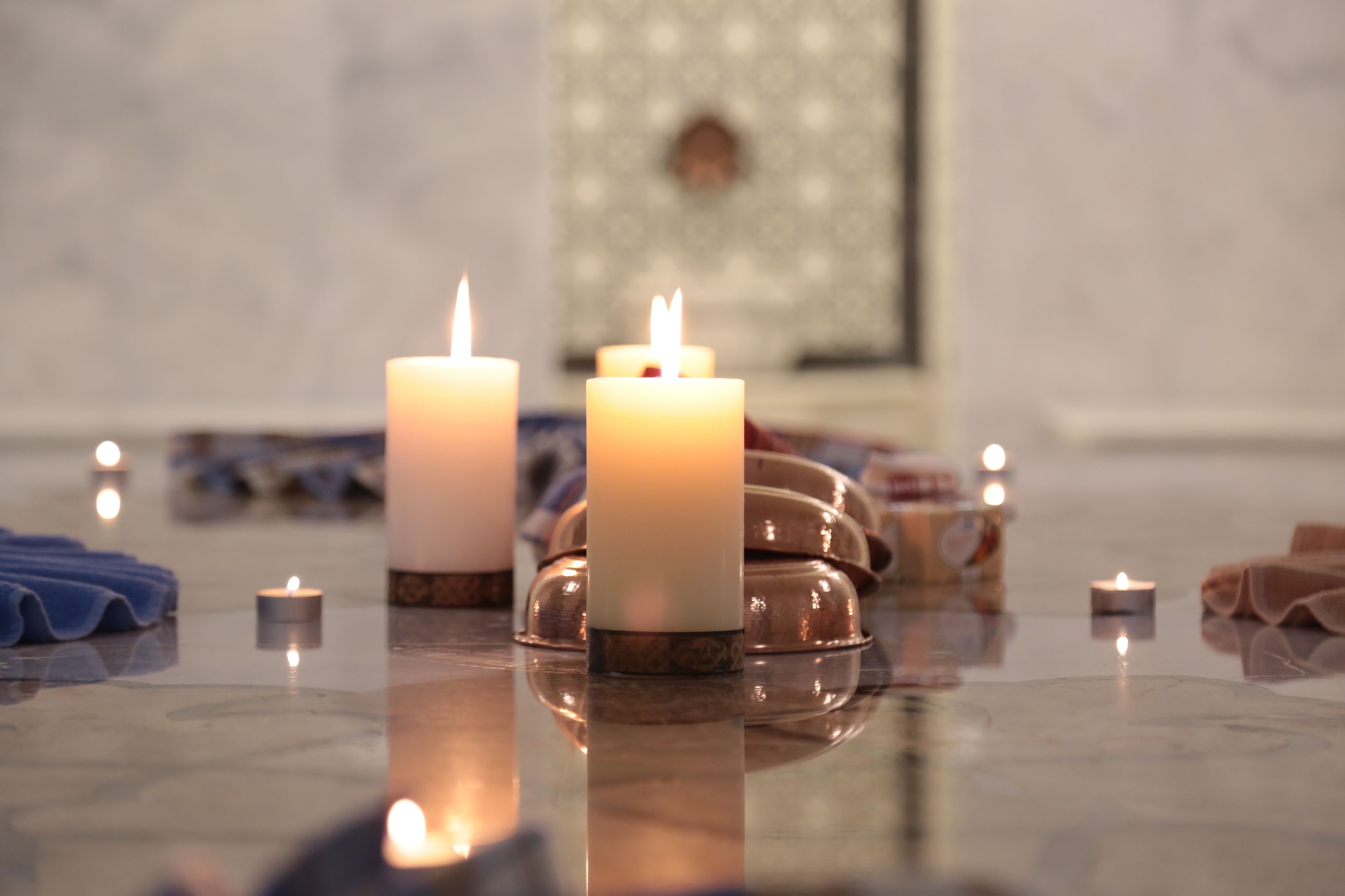 A room with a marble floor, several candles, and a patterned wall.