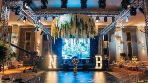 A stage with a backdrop, stage lights, and a floral arrangement.