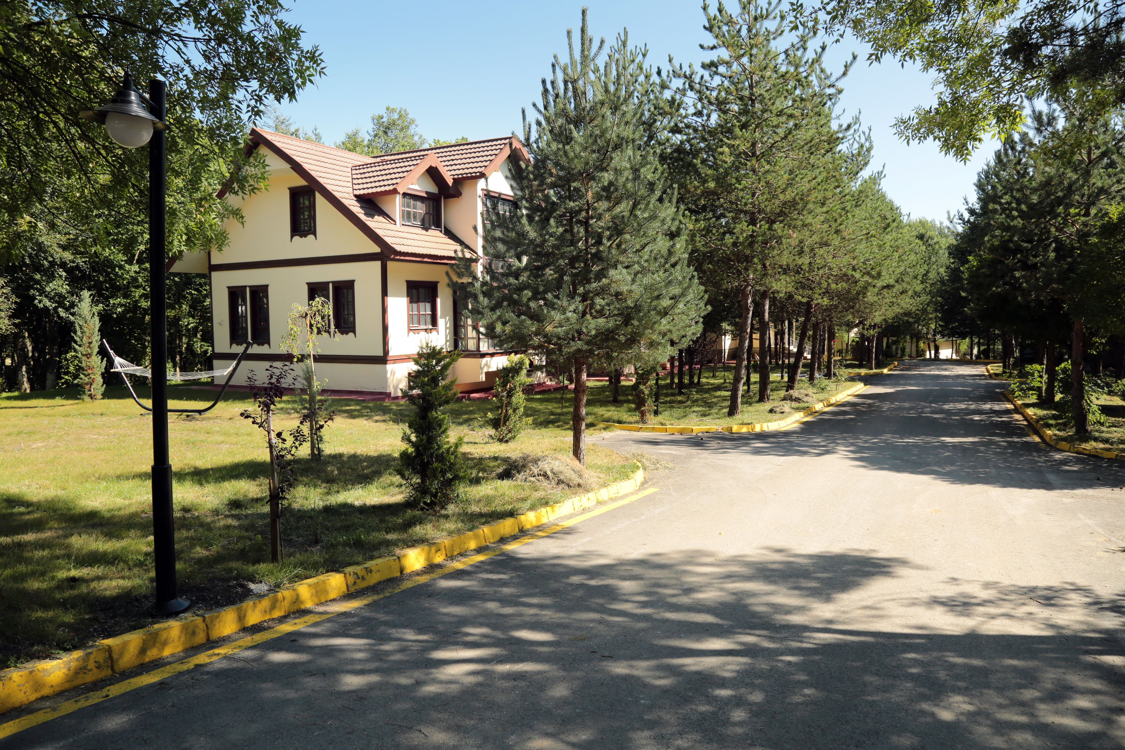 A two-story house with a sloped roof and a visible chimney, surrounded by a well-maintained lawn and trees.