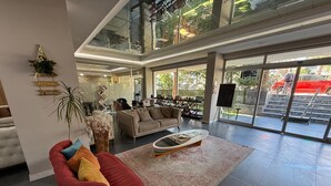 A spacious living area with a high ceiling, a red armchair, a beige sofa, and a coffee table. - On Hotel (Antalya)