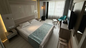 A modern hotel room with a large bed, bedside tables, a desk, a chair, and a TV. - On Hotel (Antalya)