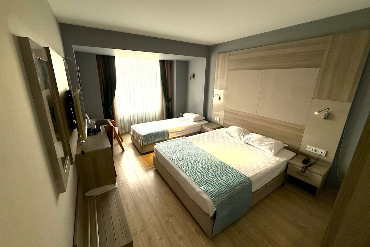 A hotel room with two beds, a desk, a chair, and a wardrobe.