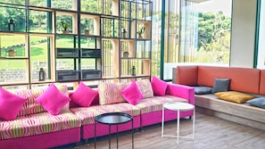 A modern living room with a pink sofa, a round coffee table, and an orange couch.