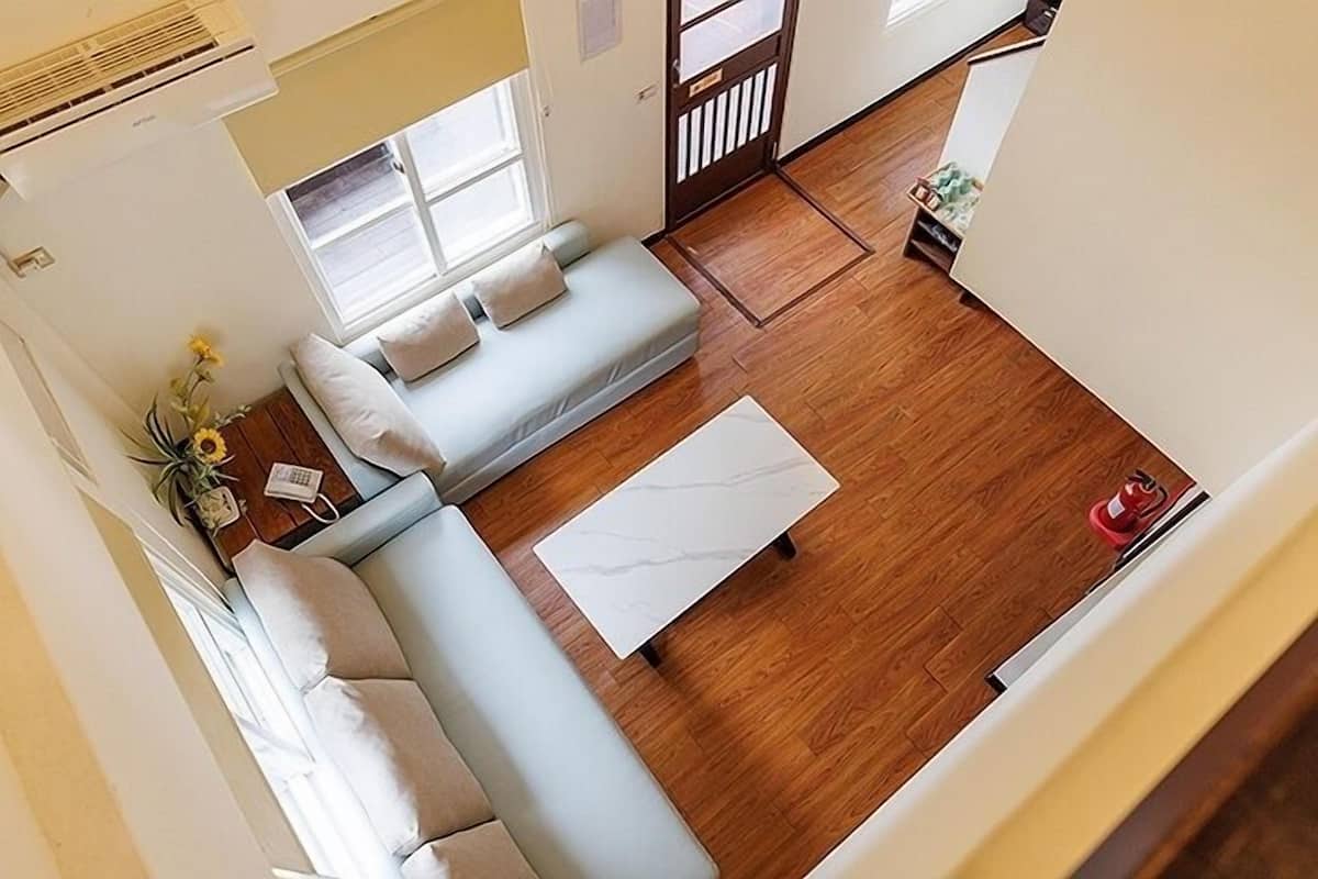 Uma sala de estar moderna com um sofá azul claro, uma mesa de centro branca e piso de madeira.