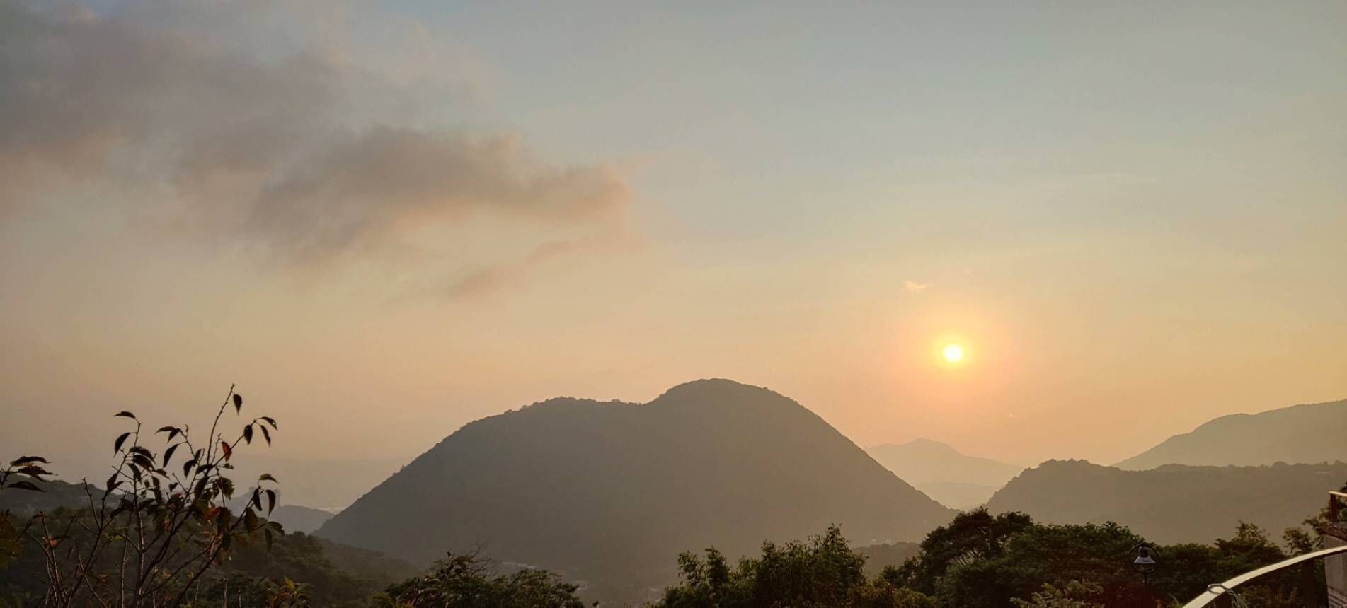 A mountainous landscape with a setting sun.