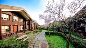 A traditional wooden building with a stone pathway and cherry blossom trees. - Yanmin Hot Spring Resort (Taipei)