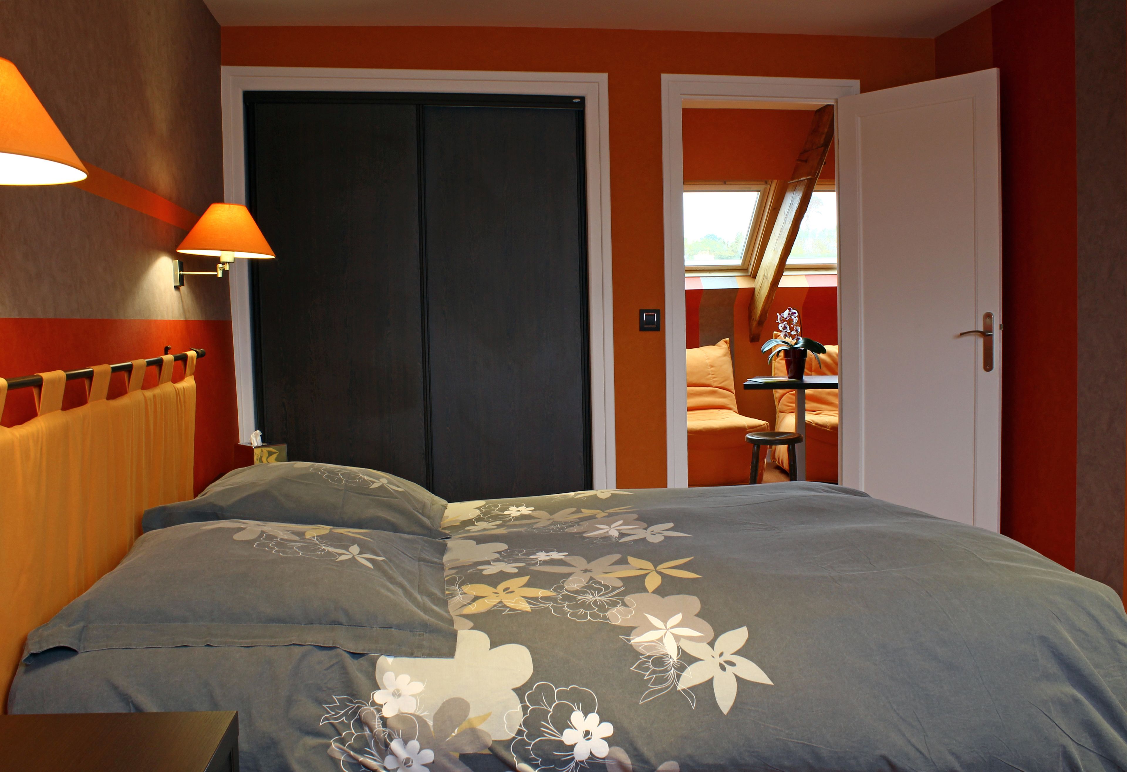 A bedroom with a bed, a wardrobe, and a door leading to another room.