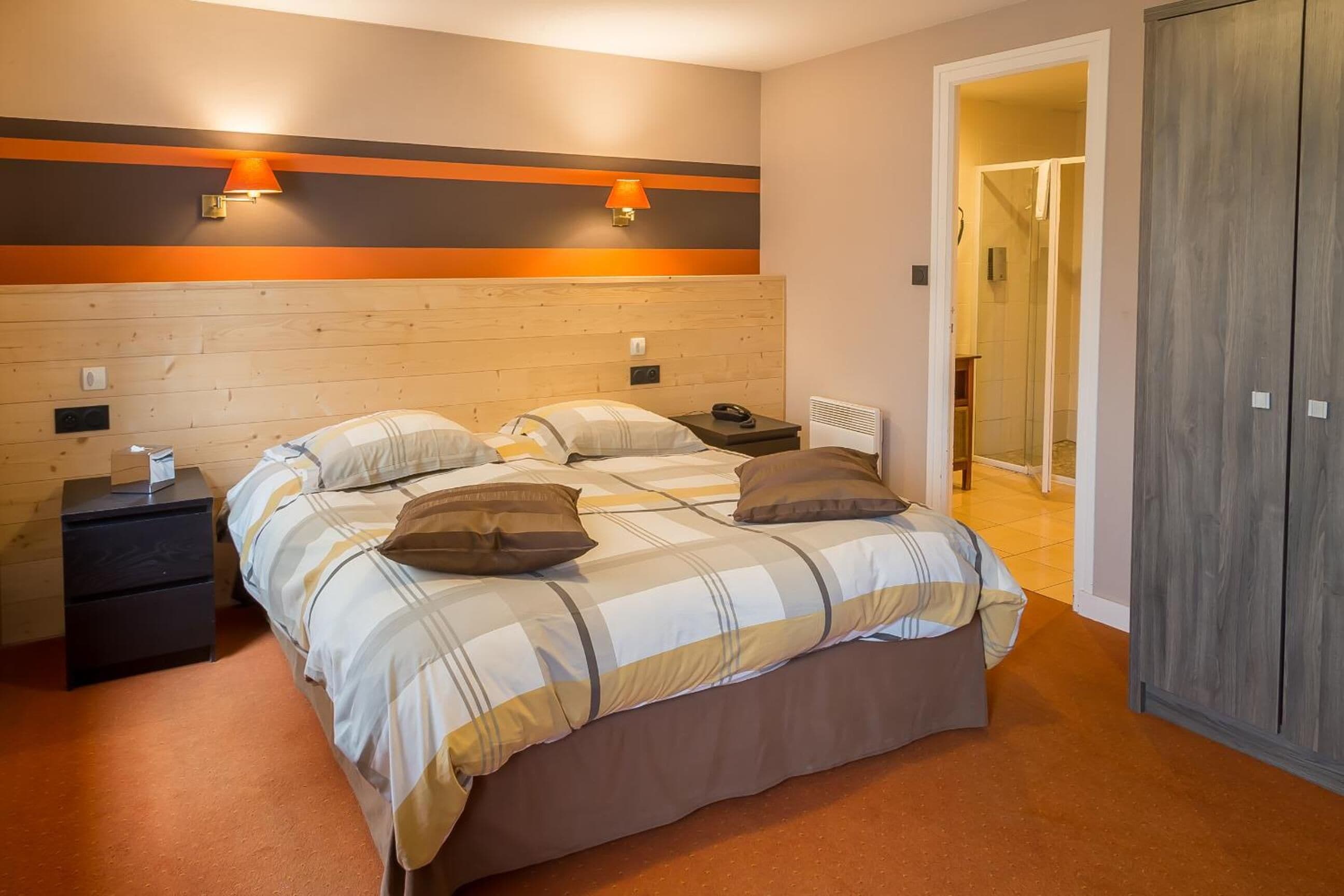 Ein Schlafzimmer mit einem hölzernen Kopfteil, zwei Nachttischen, einem Bett mit gestreifter Bettdecke und einem Kleiderschrank.