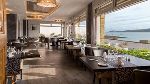 A modern restaurant with a view of the sea, featuring wooden flooring, contemporary furniture, and large windows. - Hostellerie de la Mer (Crozon)