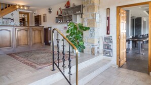 A spacious kitchen with wooden cabinets, a stone accent wall, and a staircase leading to a dining area. - Hostellerie de la Mer (Crozon)